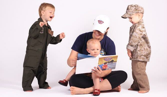 woman reading book to three young boys