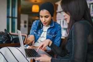 two women pointing at laptop