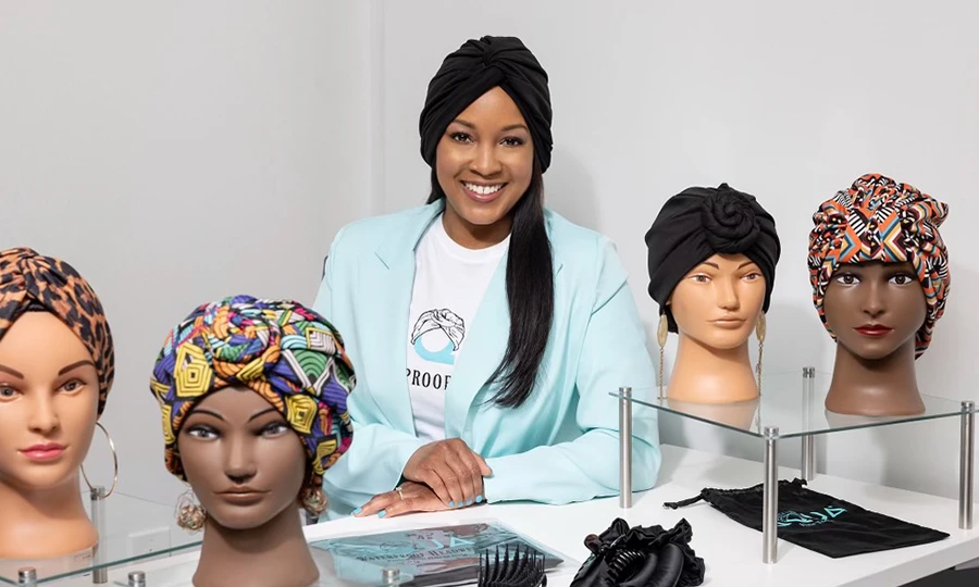 Khadijah wearing one of her turbans with several other headware options on mannequins